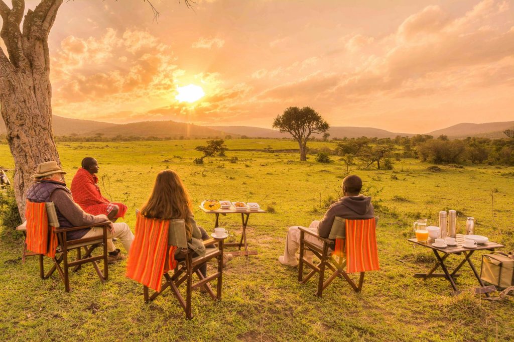 Luxury safari guests enjoying an outdoor breakfast in the African wilderness at sunrise – private Kenya and Tanzania safari holiday, authentic cultural experience, wildlife viewing, and tailor-made East Africa tours with Cotis Safaris